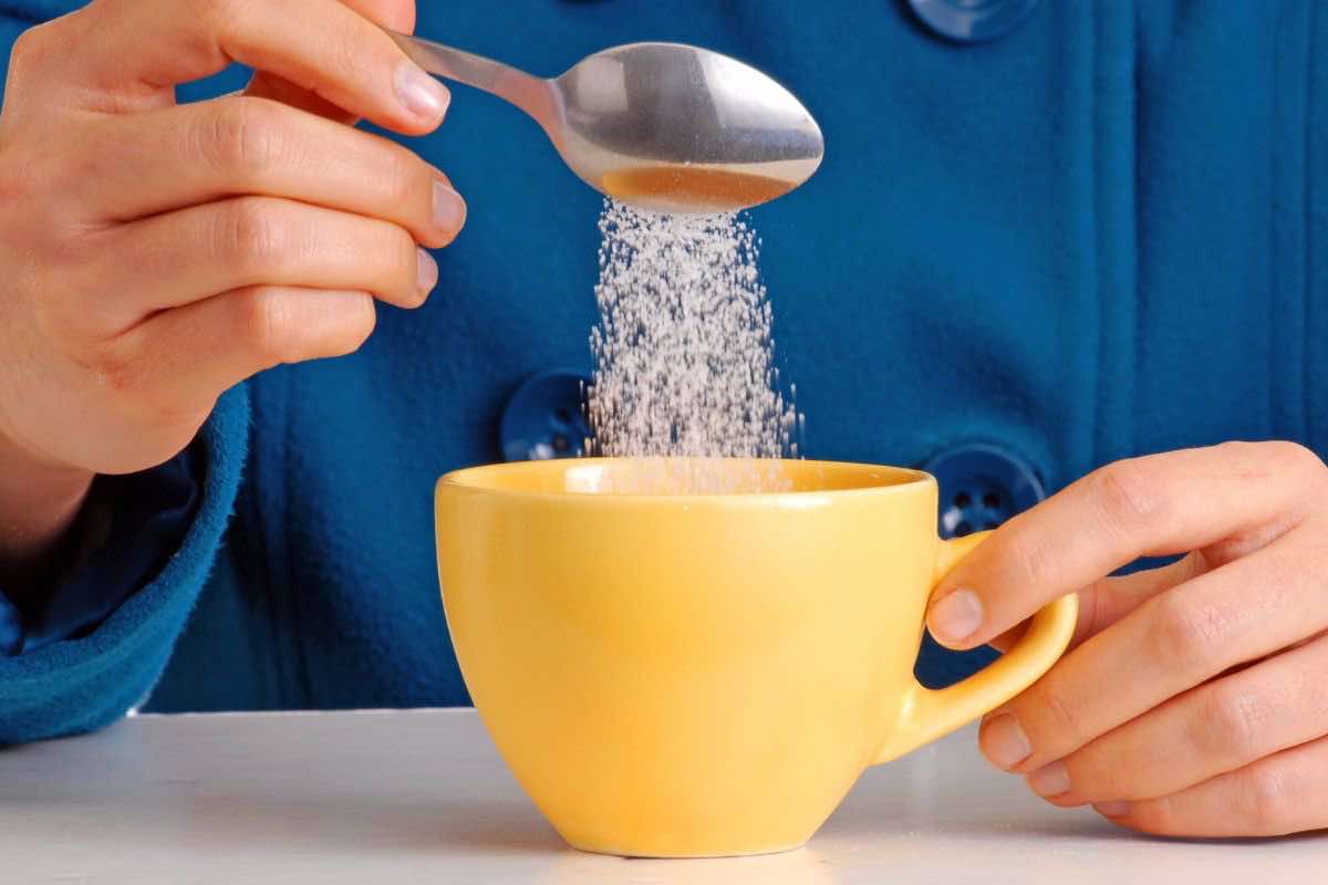 Persona che aggiunge zucchero al caffè